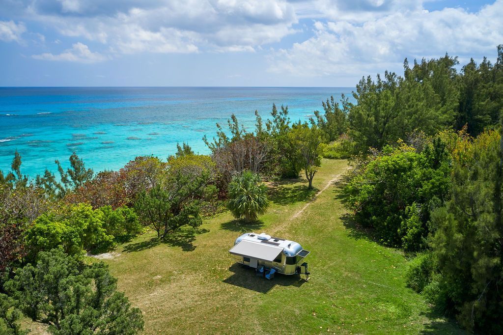 RV on grassy bluff overlooking turquoise ocean and cloudy sky, Warwick Long Bay
