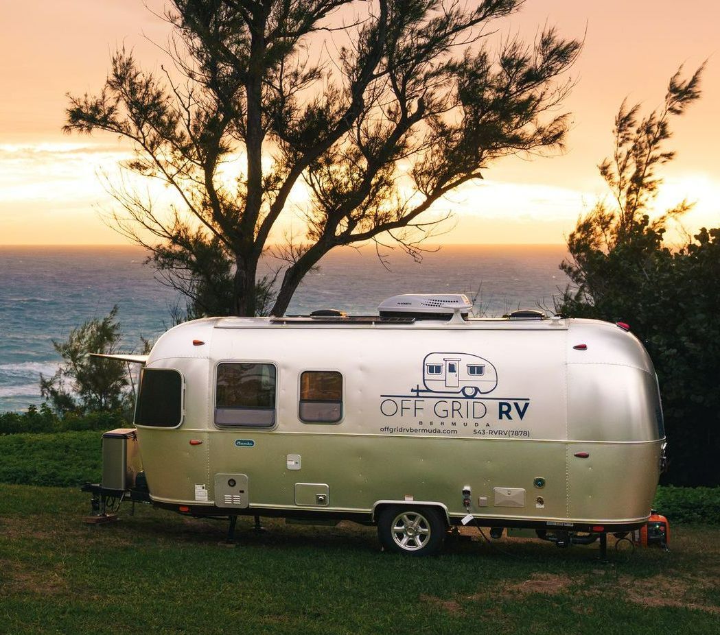 Off Grid RV overlooking ocean at sunset, surrounded by trees