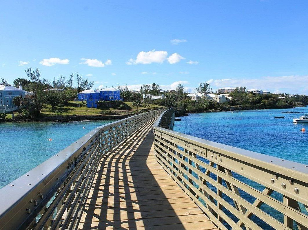 A bridge over a body of water with houses in the background.