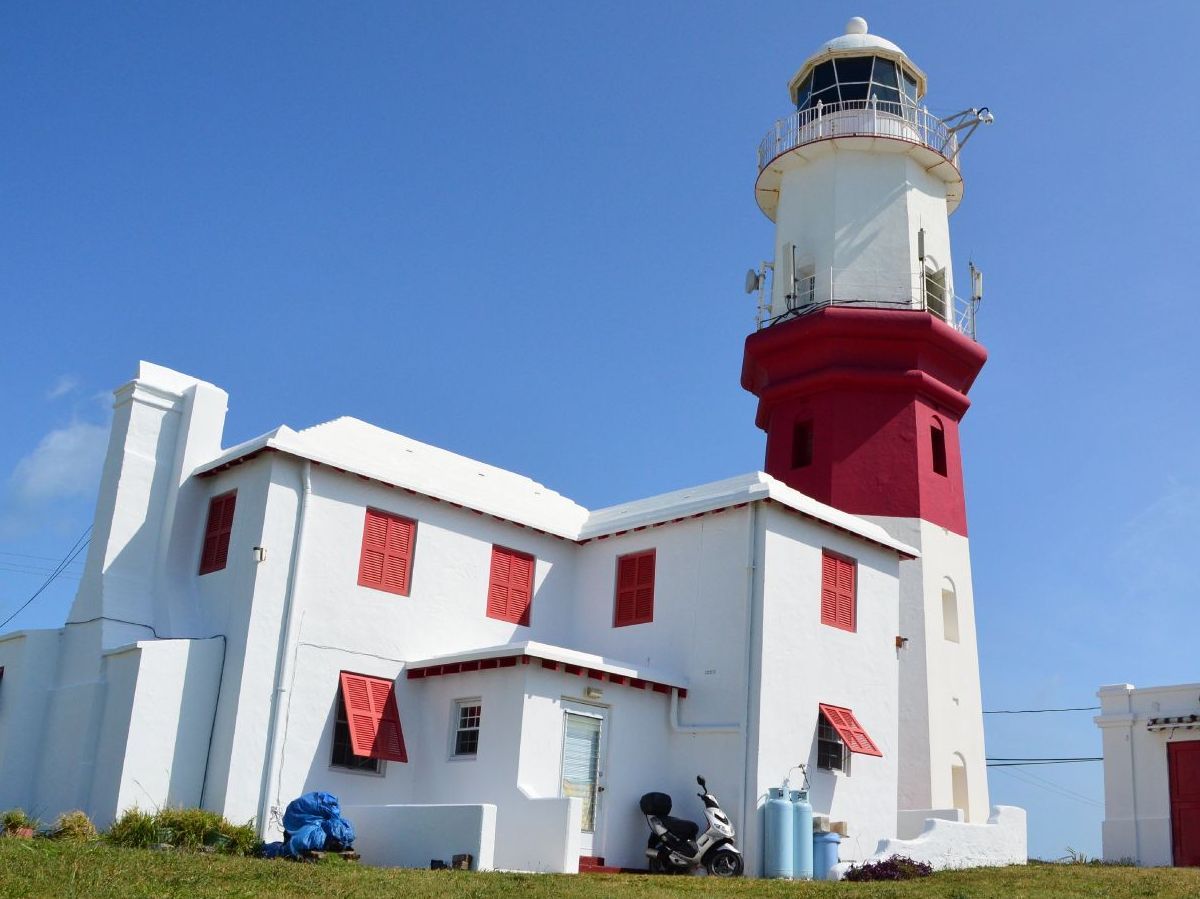A red and white lighthouse with a motorcycle parked in front of it