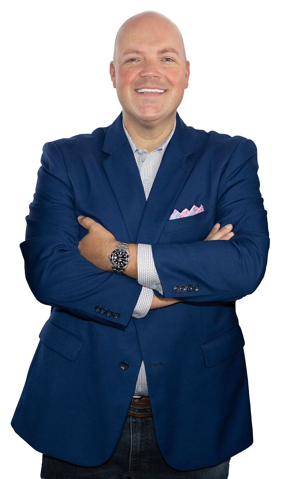 A man in a blue suit and tie is standing with his arms crossed and smiling.