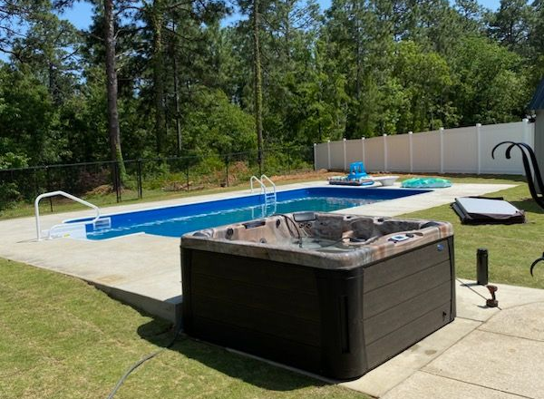 Stand alone hot tub next to an inground pool