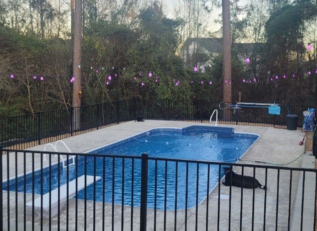 Finished outdoor, rectangular pool with rounded edges and a diving board.