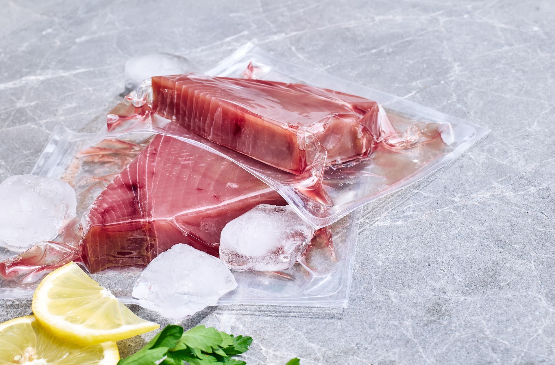 Red tuna fillets in vacuum package on gray marble.
