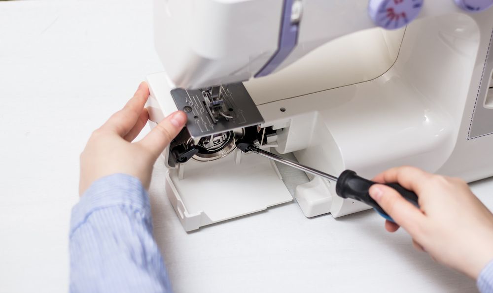 A Person is Fixing a Sewing Machine With a Screwdriver — James Hunter Mobile Sewing Machine Mechanic in Caloundra, QLD