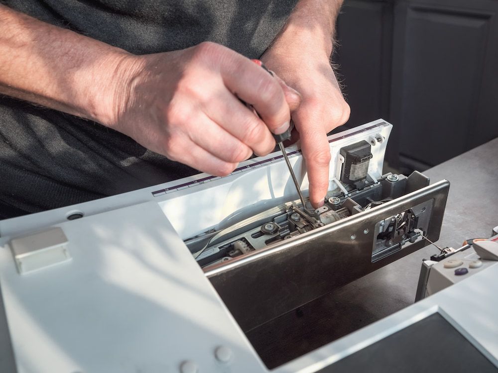 A Man is Working on a Computer With a Screwdriver — James Hunter Mobile Sewing Machine Mechanic in Caloundra, QLD
