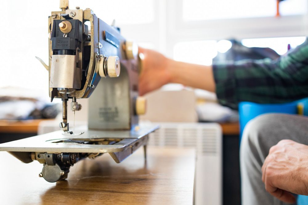 A Person is Using a Sewing Machine on a Wooden Table — James Hunter Mobile Sewing Machine Mechanic in Caloundra, QLD