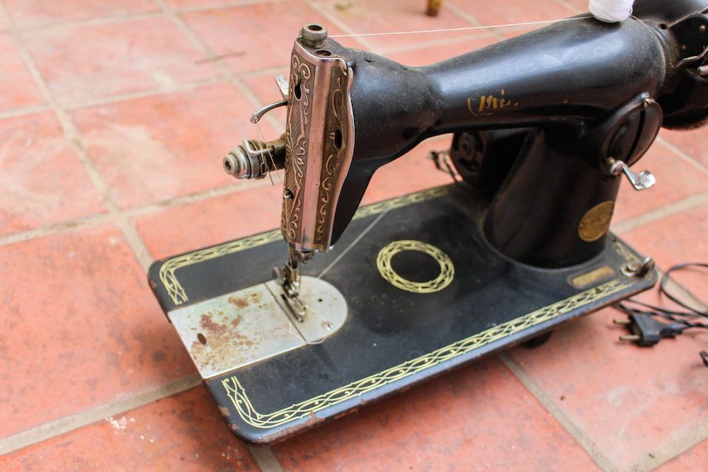 An Old Sewing Machine is Sitting on a Tiled Floor — James Hunter Mobile Sewing Machine Mechanic in Noosa, QLD