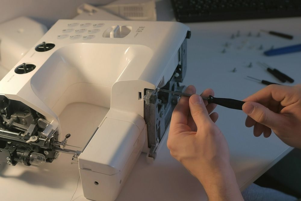 A Person is Fixing a Sewing Machine With a Screwdriver — James Hunter Mobile Sewing Machine Mechanic in Battery Hill, QLD