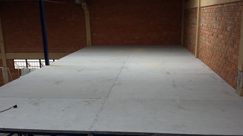 Uma grande sala vazia com piso branco e uma parede de tijolos.