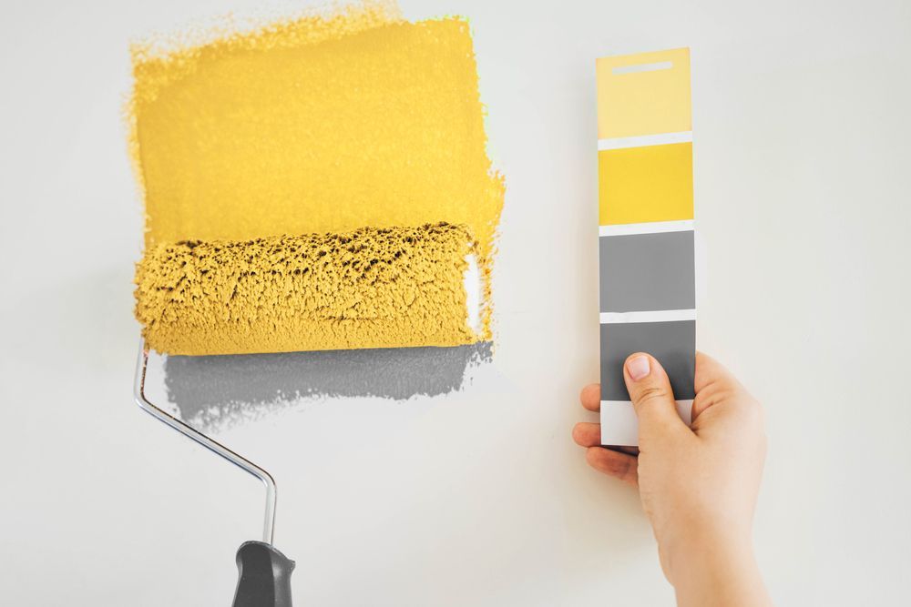 Uma pessoa está segurando uma paleta de cores ao lado de um rolo de pintura.