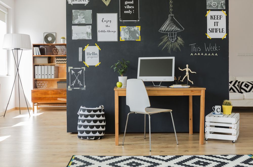 Um escritório em casa com uma parede de quadro negro e uma mesa com um computador.