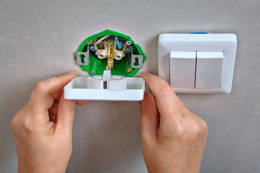Uma pessoa está instalando um interruptor de luz na parede.