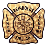 Vintage gold firefighter emblem reading “Reinholds Fire Co., Lanco. Co. Zone No. 1” with crossed axes and ladder