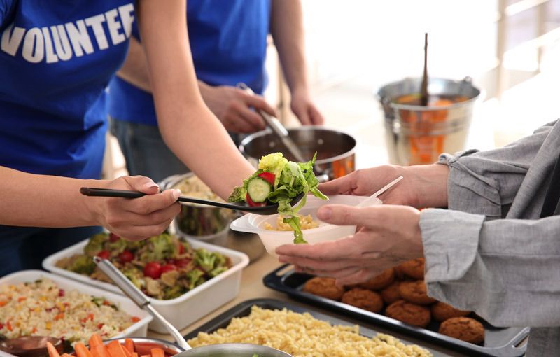 Volunteers serving salad and food at a buffet table