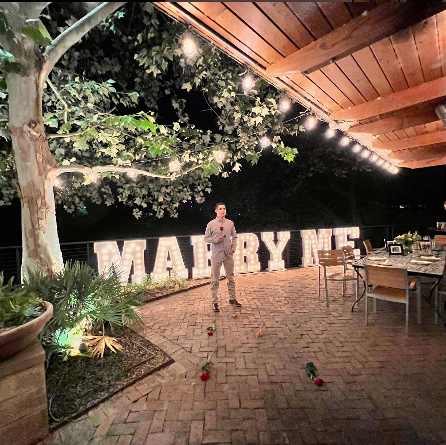 A man is standing in front of a sign that says marry me