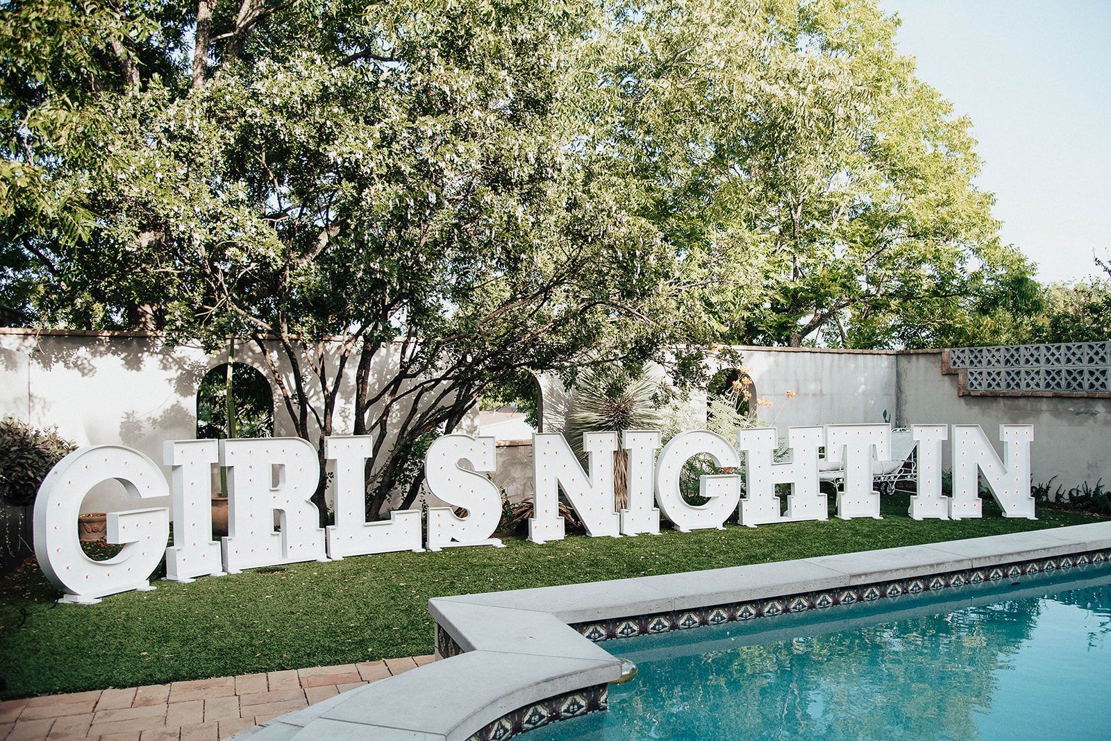 A large sign that says `` girls night in '' is sitting next to a pool.