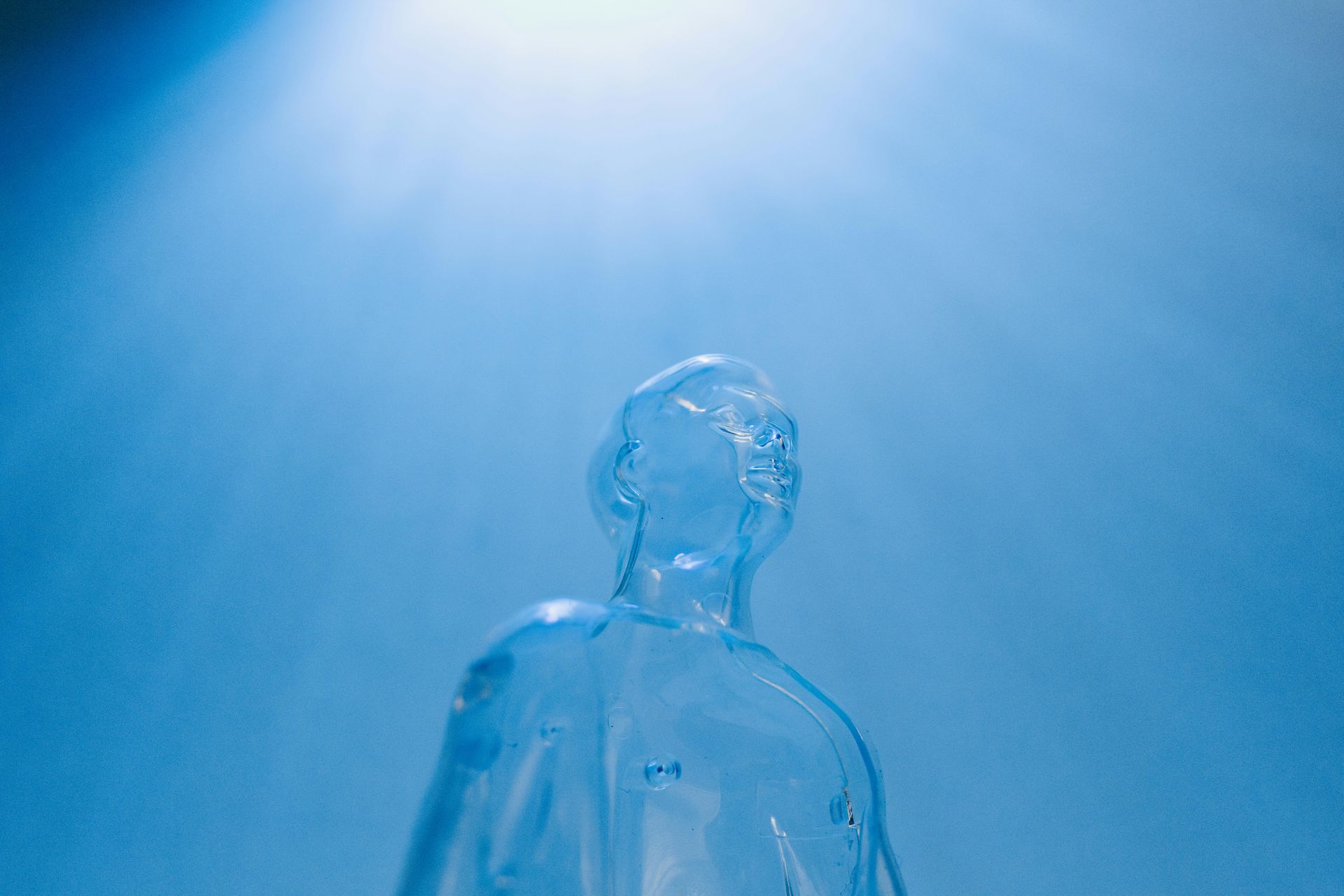 Figura umana blu traslucida che si protende verso una luce intensa sott'acqua.