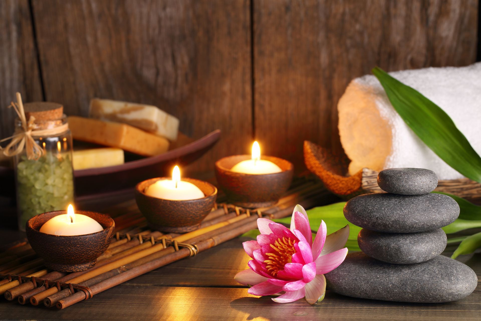 Spa still life: lit candles, stacked stones, lotus flower, towel, and aromatherapy products on wood. Spa still life: lit candles, stacked stones, lotus flower, towel, and aromatherapy products on wood.