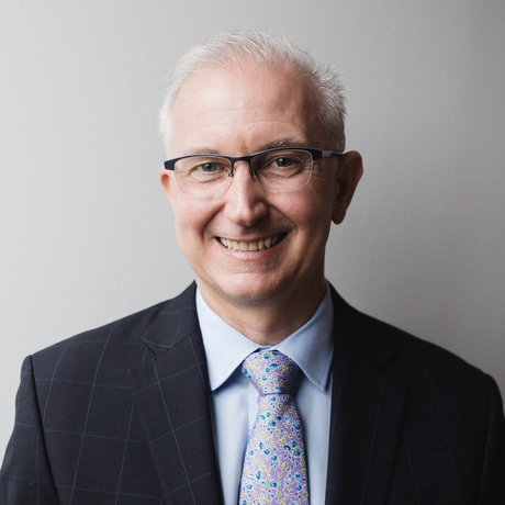 A man in a suit and tie is smiling for the camera.