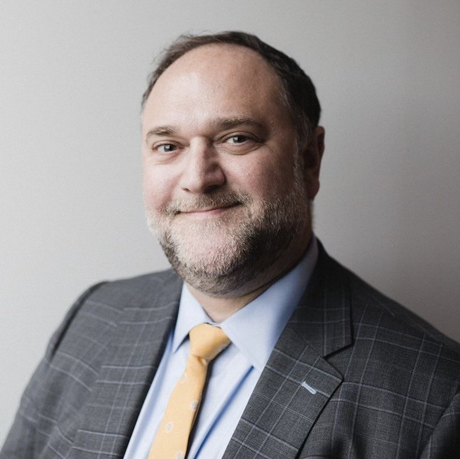 A man in a suit and tie is smiling for the camera