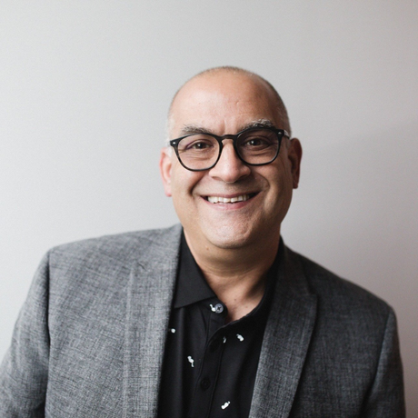 A man wearing glasses and a suit is smiling for the camera.
