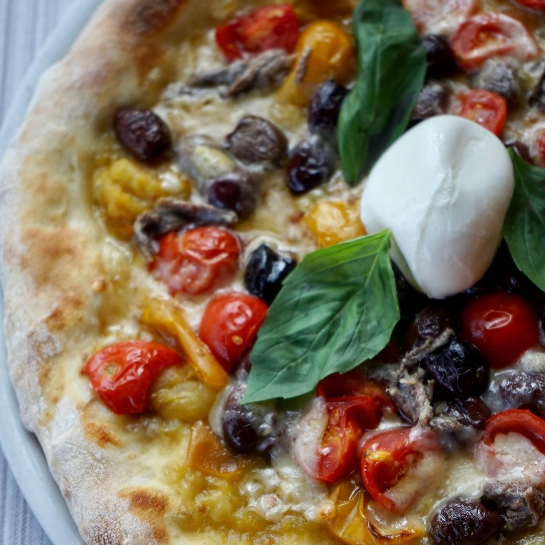 Pizza con pomodorini freschi, olive nere e mozzarella di bufala
