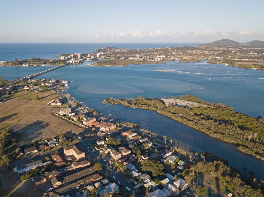An Aerial View Of A Body Of Water Surrounded By Houses And Trees — Bulley Roof Restoration, Painting & Pressure Cleaning in Forster-Tuncurry, NSW