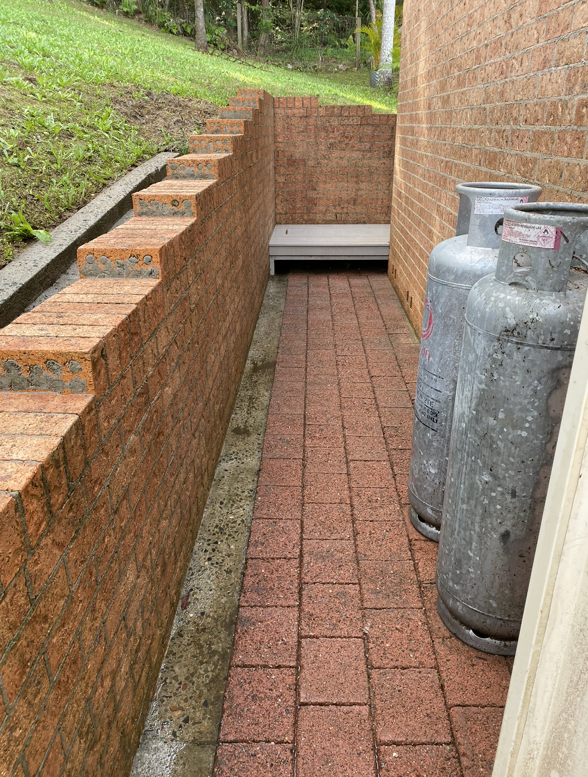 A Row of Gas Bottles Sitting on A Sidewalk Next to A Brick Wall After — Bulley Roof Restoration, Painting & Pressure Cleaning in Wingham, NSW