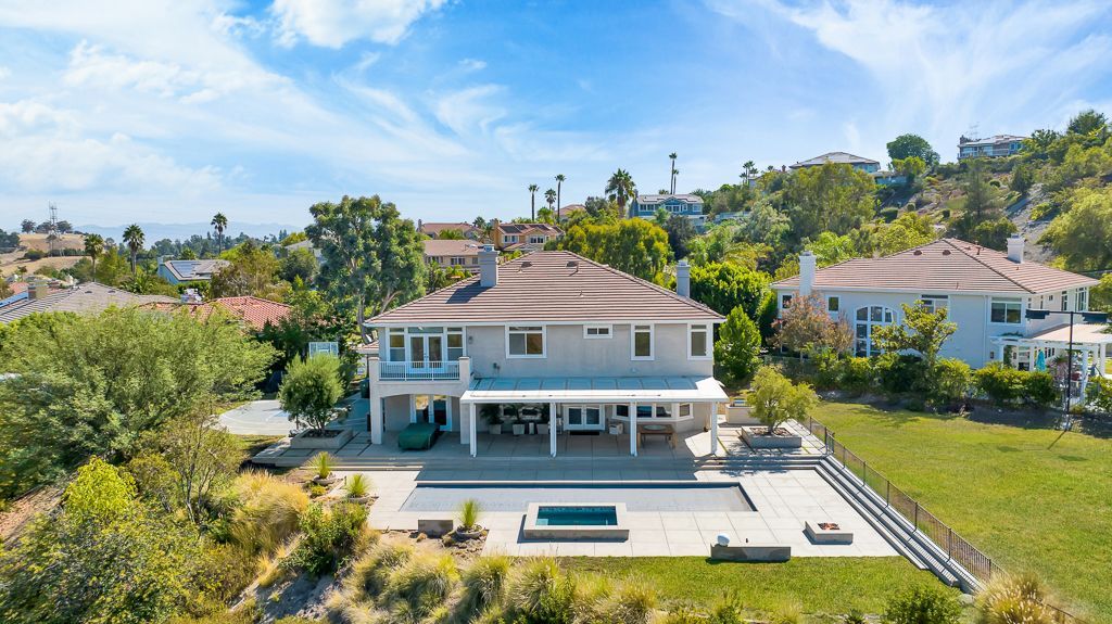 An aerial view of a large house sitting on top of a hill surrounded by trees.