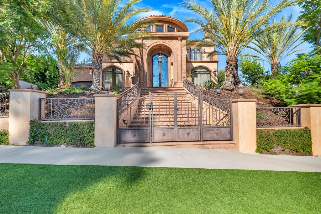 A large house with a gate and palm trees in front of it.
