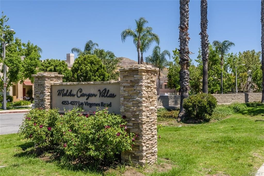 A sign for wildfire canyon villas is surrounded by palm trees