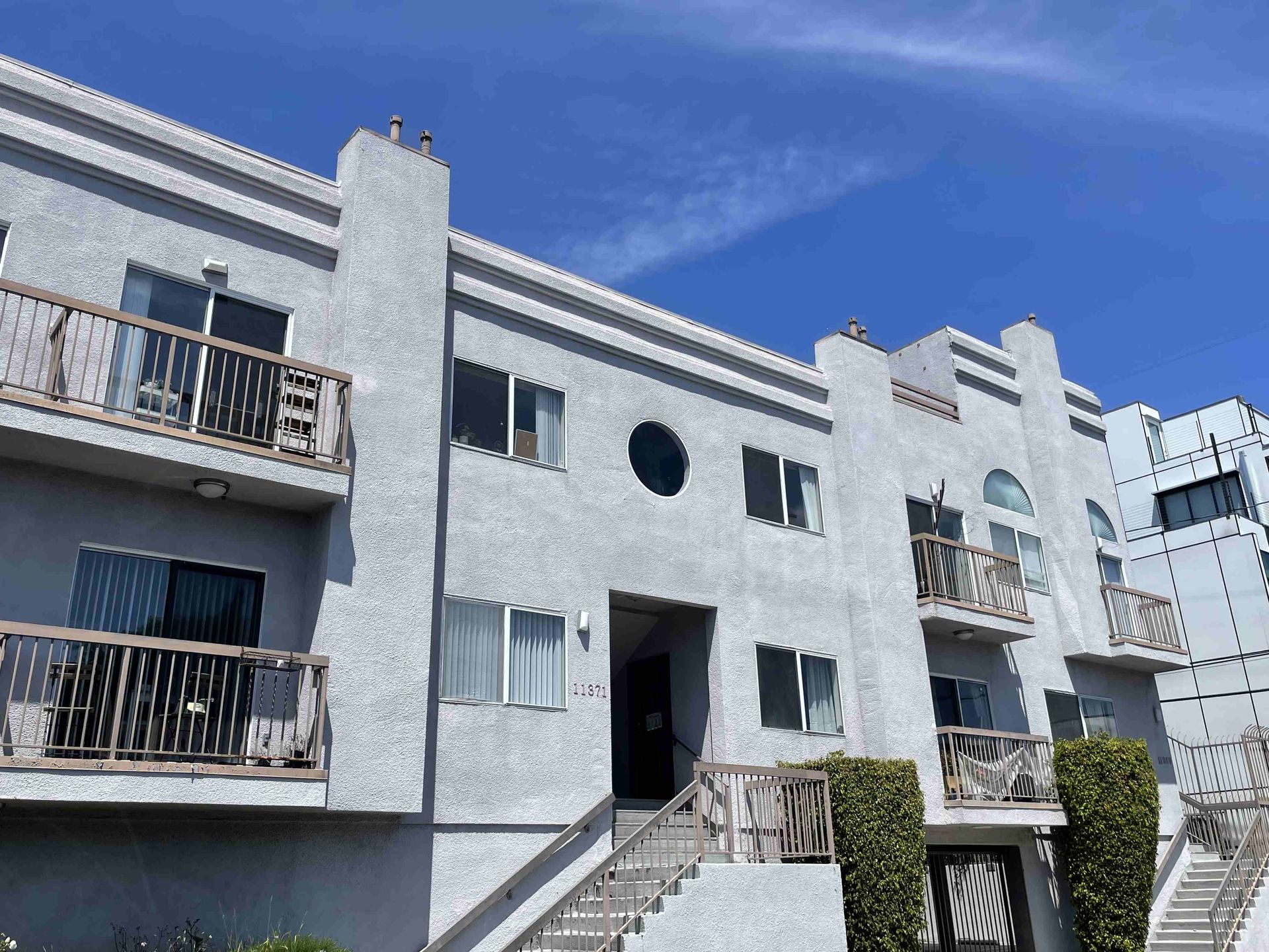 A large white apartment building with balconies and stairs