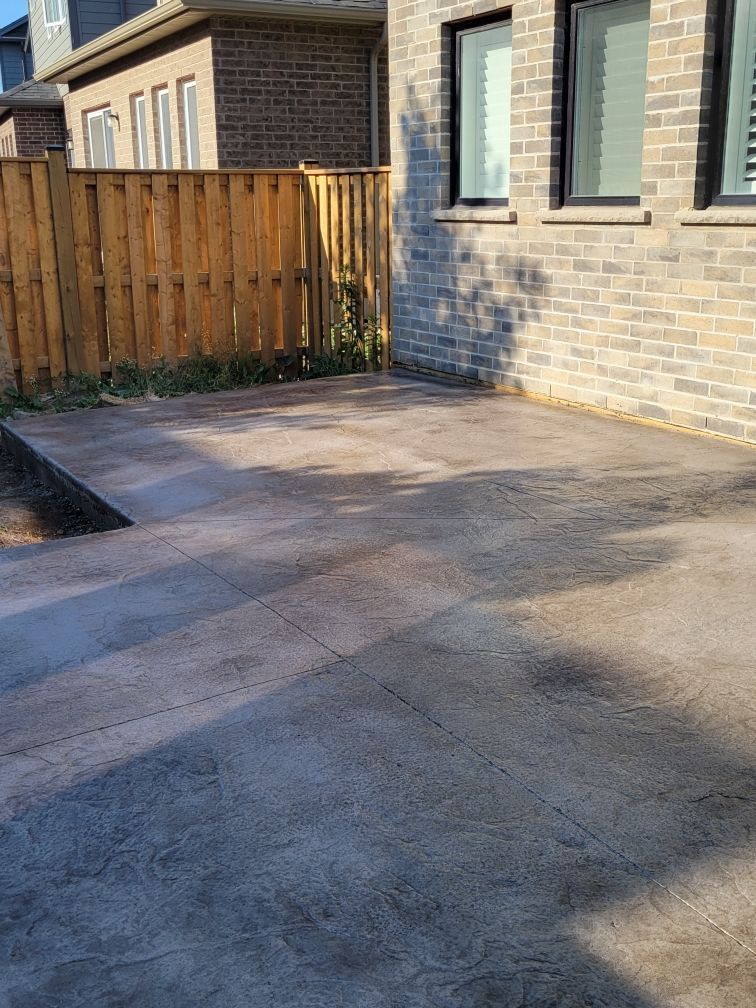 Concrete driveway beside brick house and wooden fence in daylight