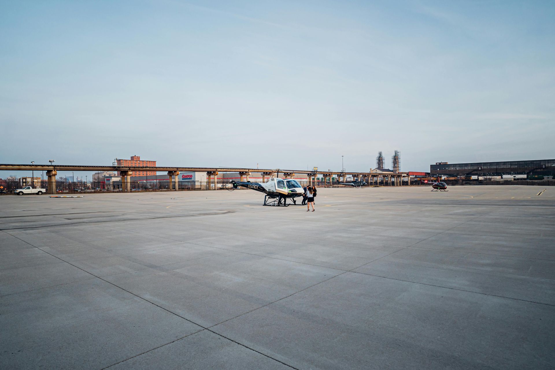 Small airplane parked on a wide concrete airfield under a pale blue sky