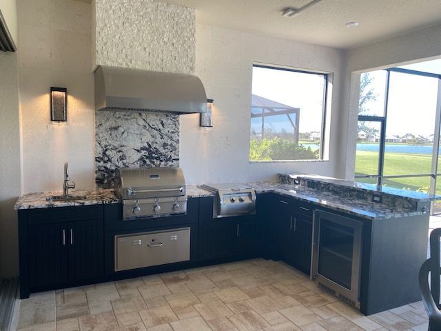 Modern kitchen with dark cabinets, stainless appliances, granite counters, and a window overlooking water.