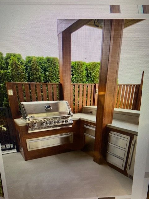 Covered outdoor patio with built-in stainless steel grill, wood posts, and cushioned bench seating