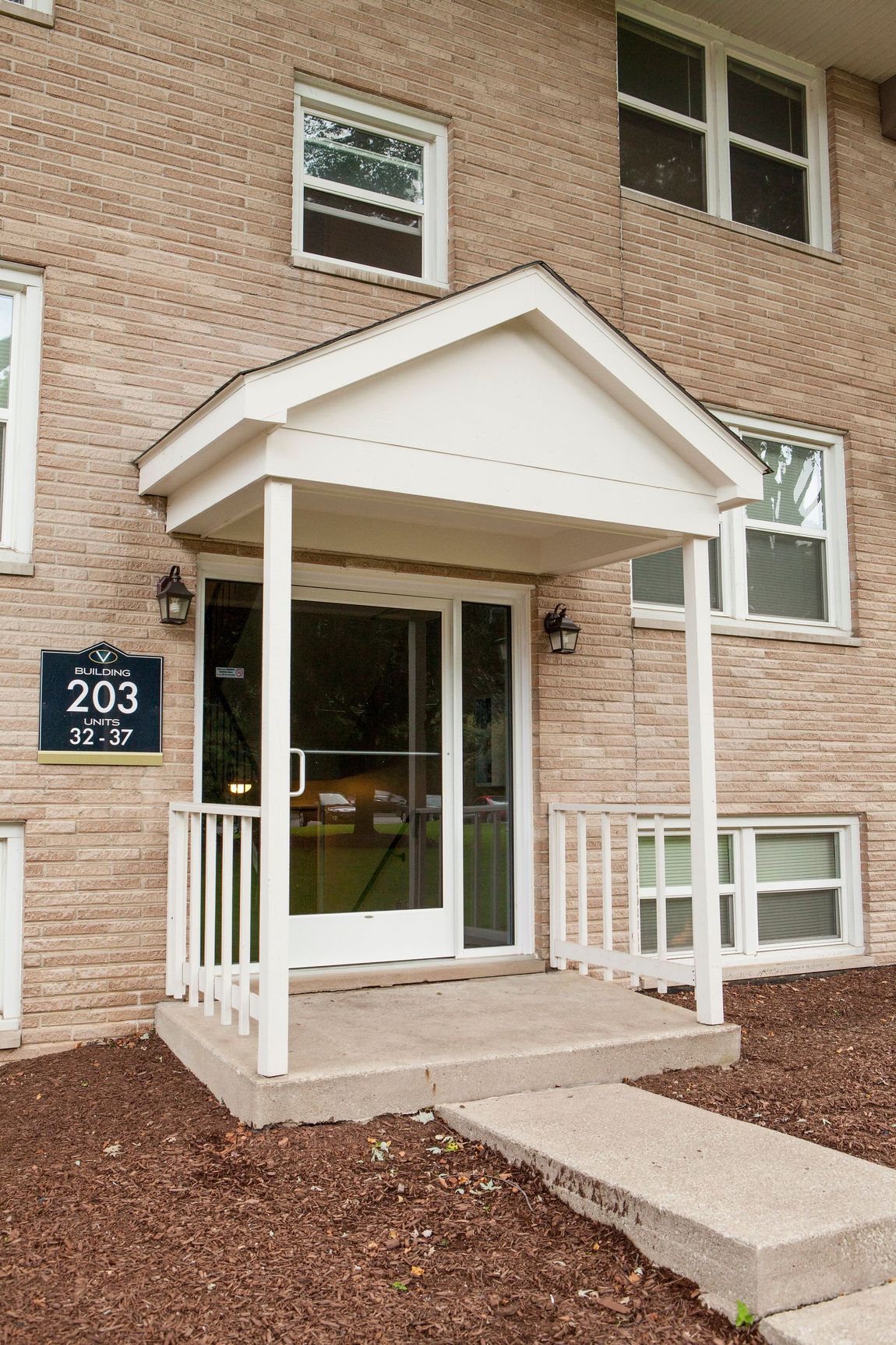 Apartment entrance with a light-colored awning, door, and address 203. Brick building exterior.