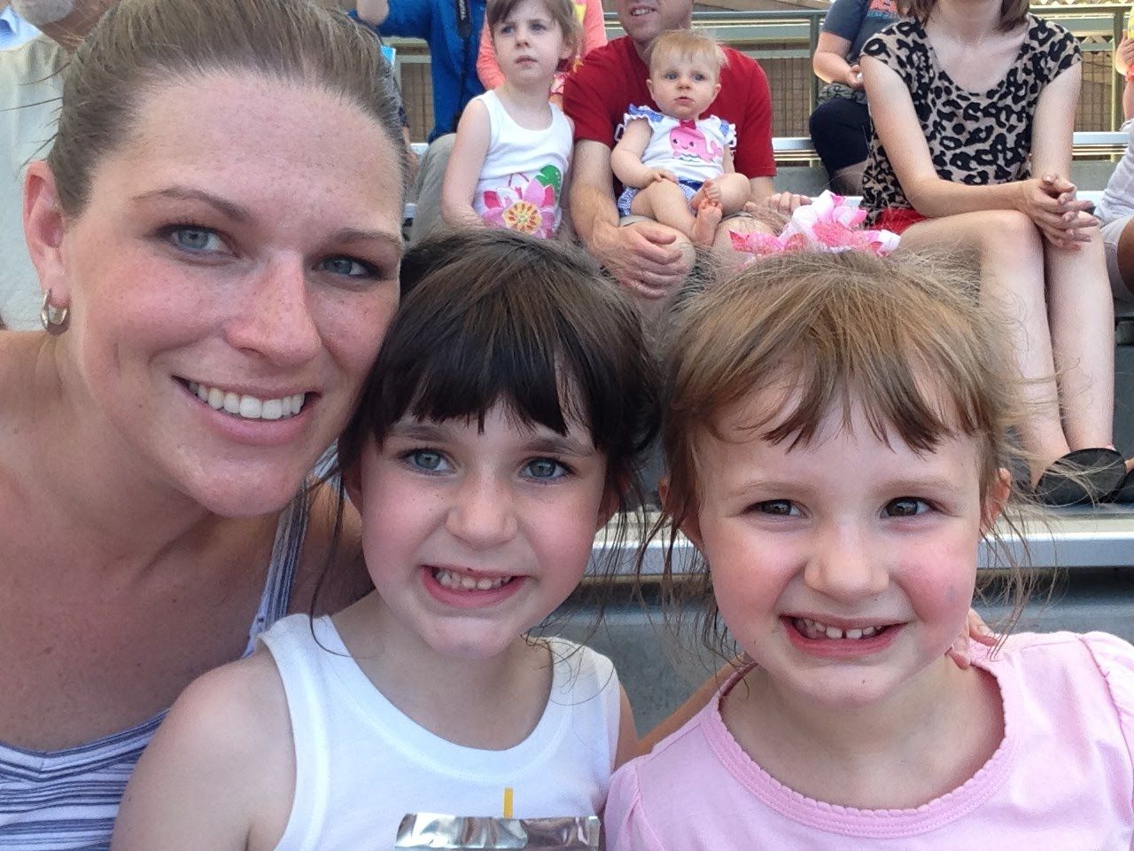 Smiling woman with two young girls sitting together in front of an audience