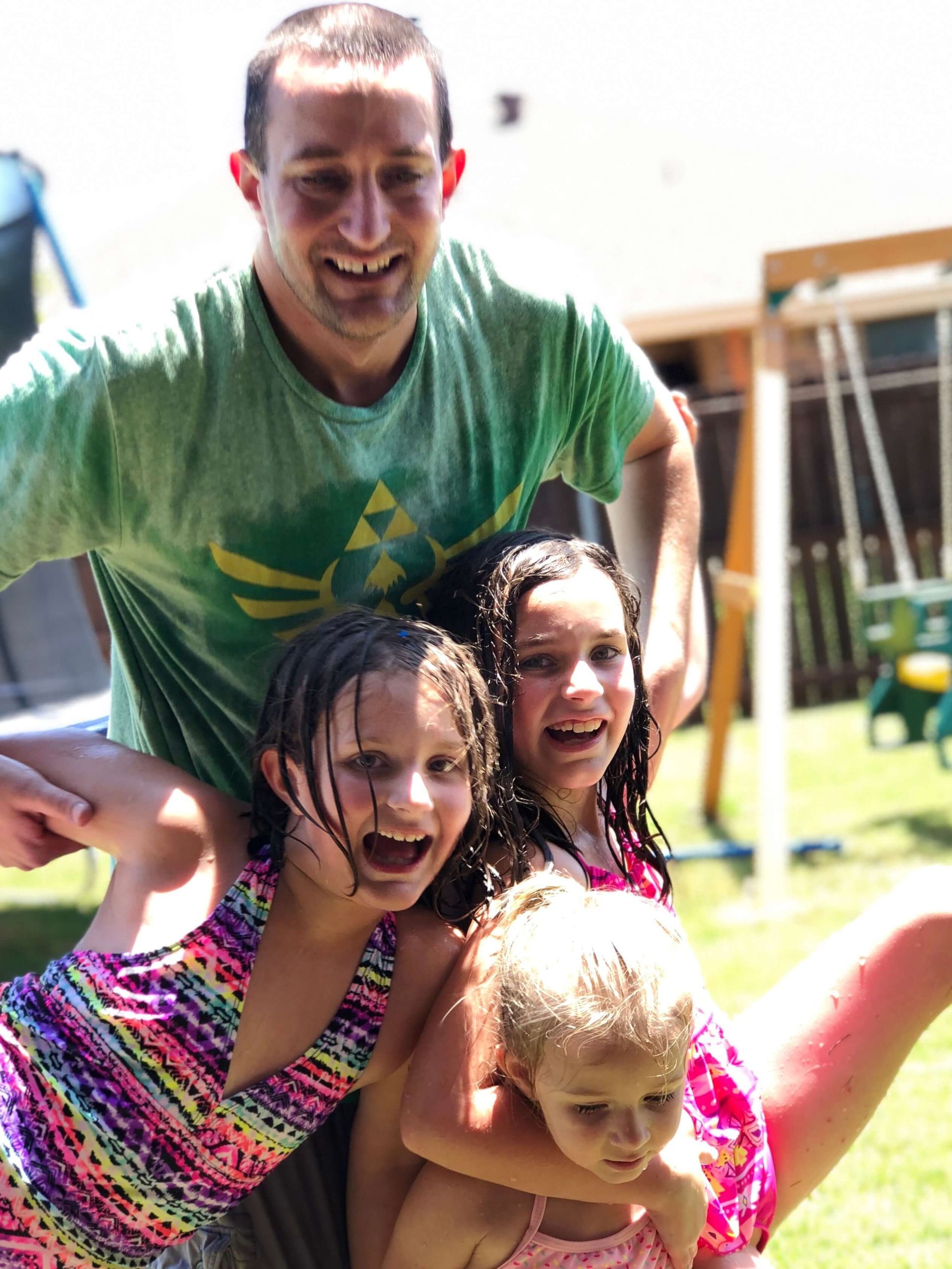 Four people smiling and posing together outdoors in bright sunlight