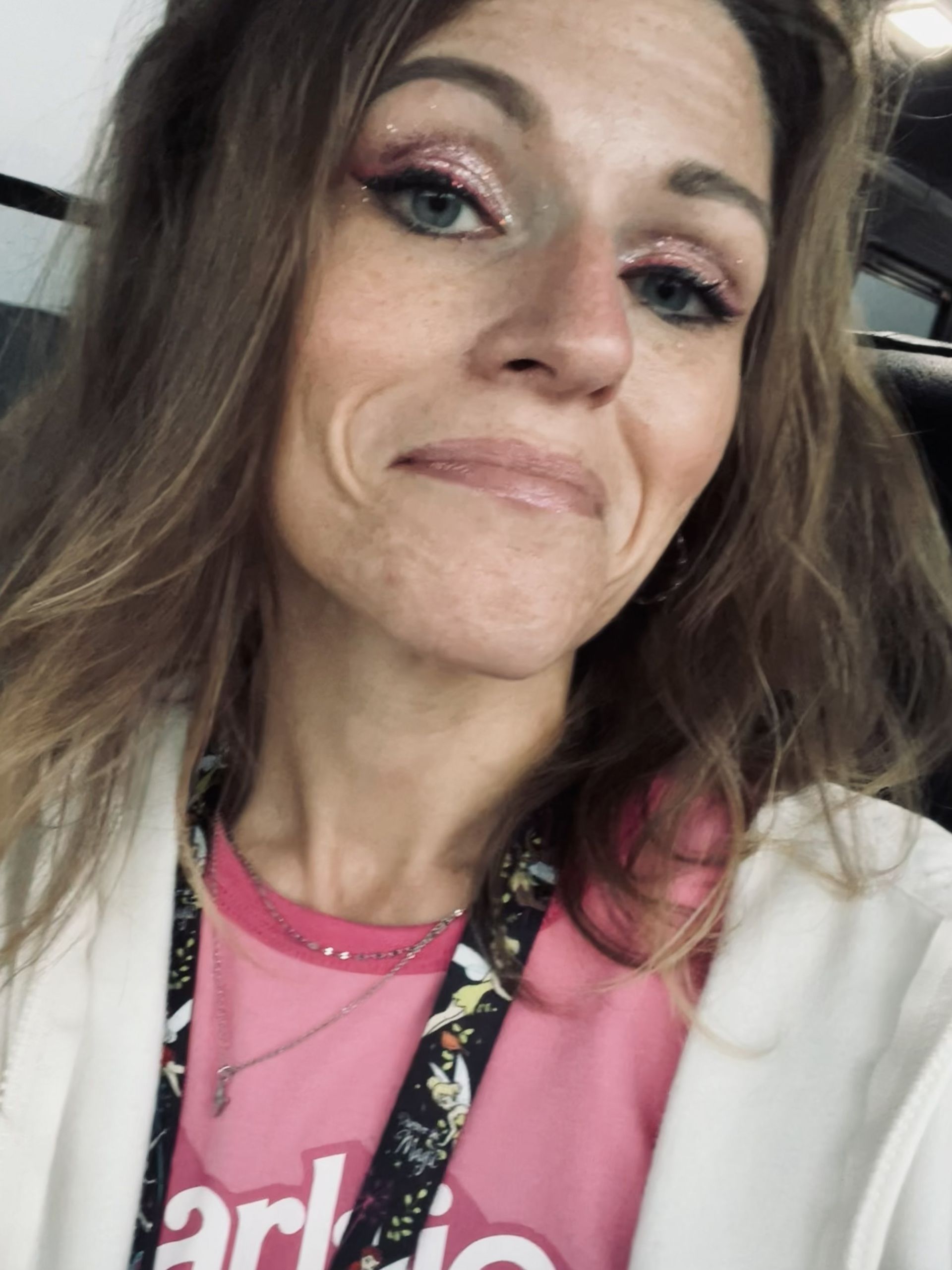 Holly in pink shirt and white jacket, smiling at the camera in her bus.