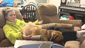 Woman lounging on a recliner with a brown dog in a cozy living room