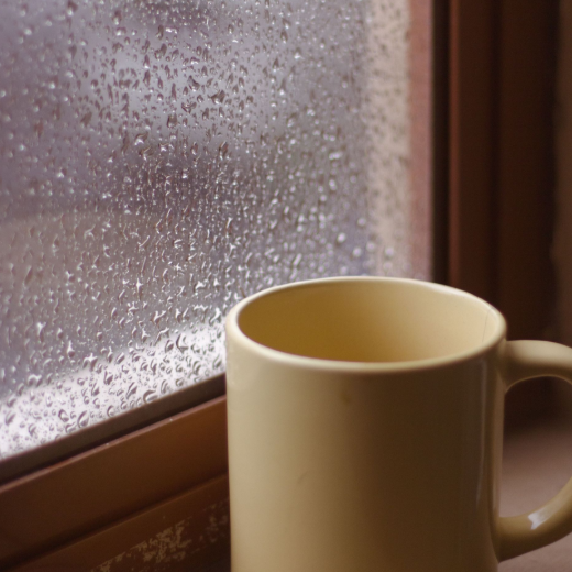 Beige mug by a rain-speckled window in warm light