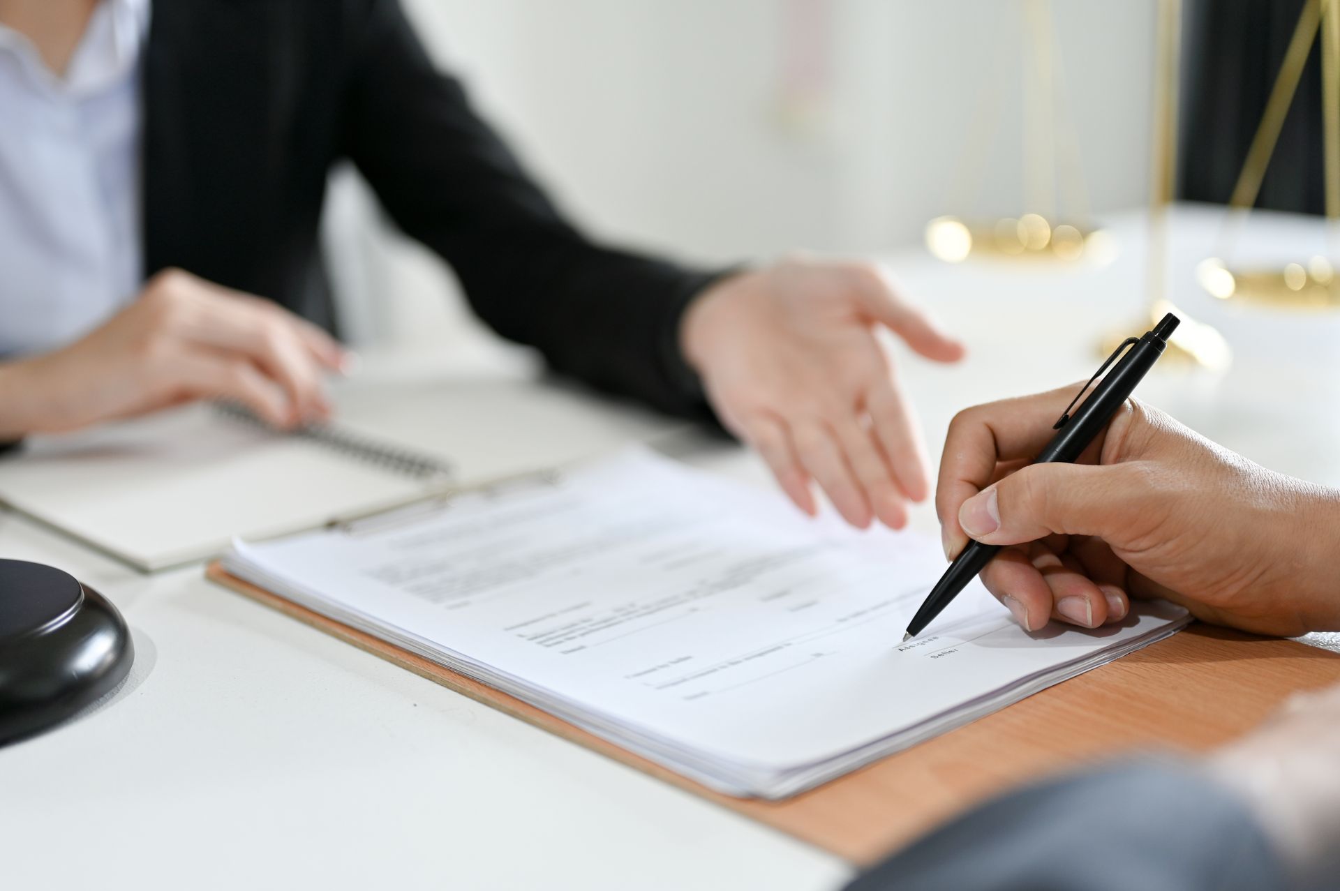 Man in suit with hands clasped behind a golden balance scale on a wooden table. Man in suit with hands clasped behind a golden balance scale on a wooden table.