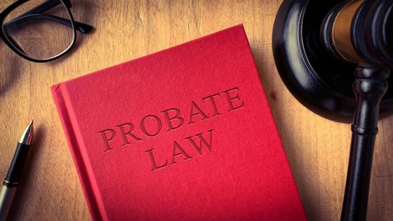 Red Probate Law book, gavel, glasses, and pen on a wooden desk.