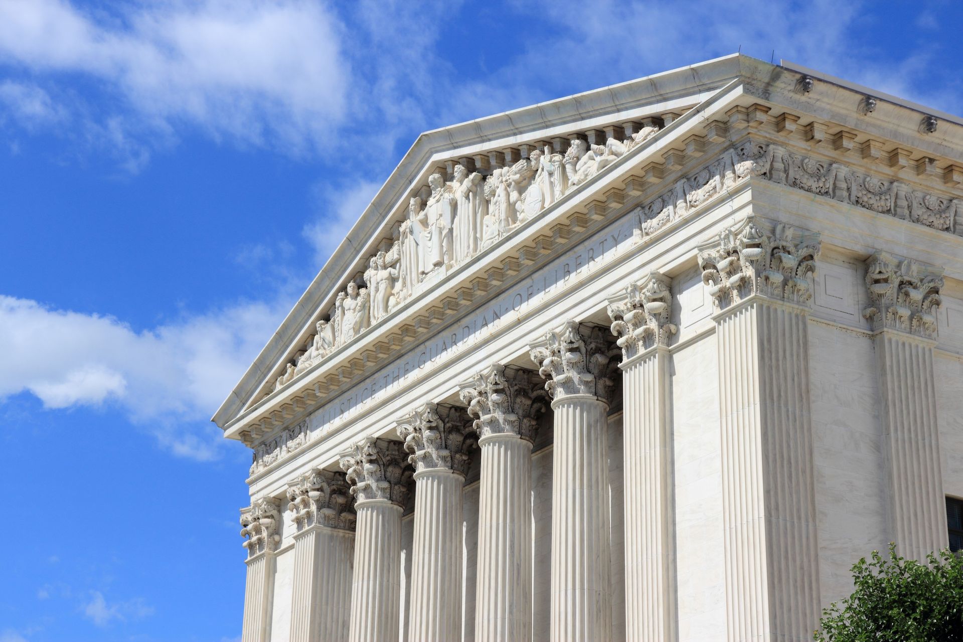 White marble Supreme Court building with columns against a blue sky.