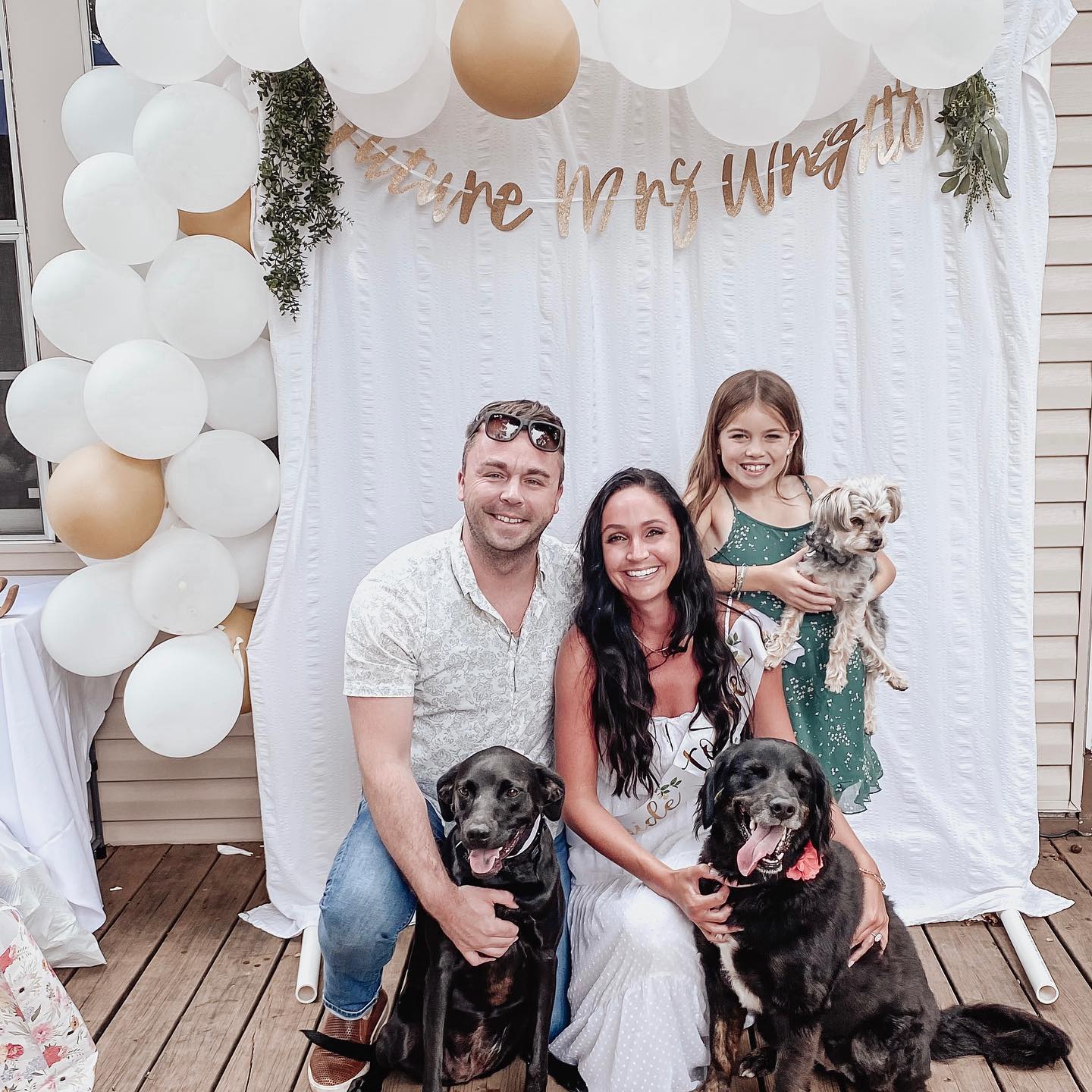 A family is posing for a picture with their dogs.