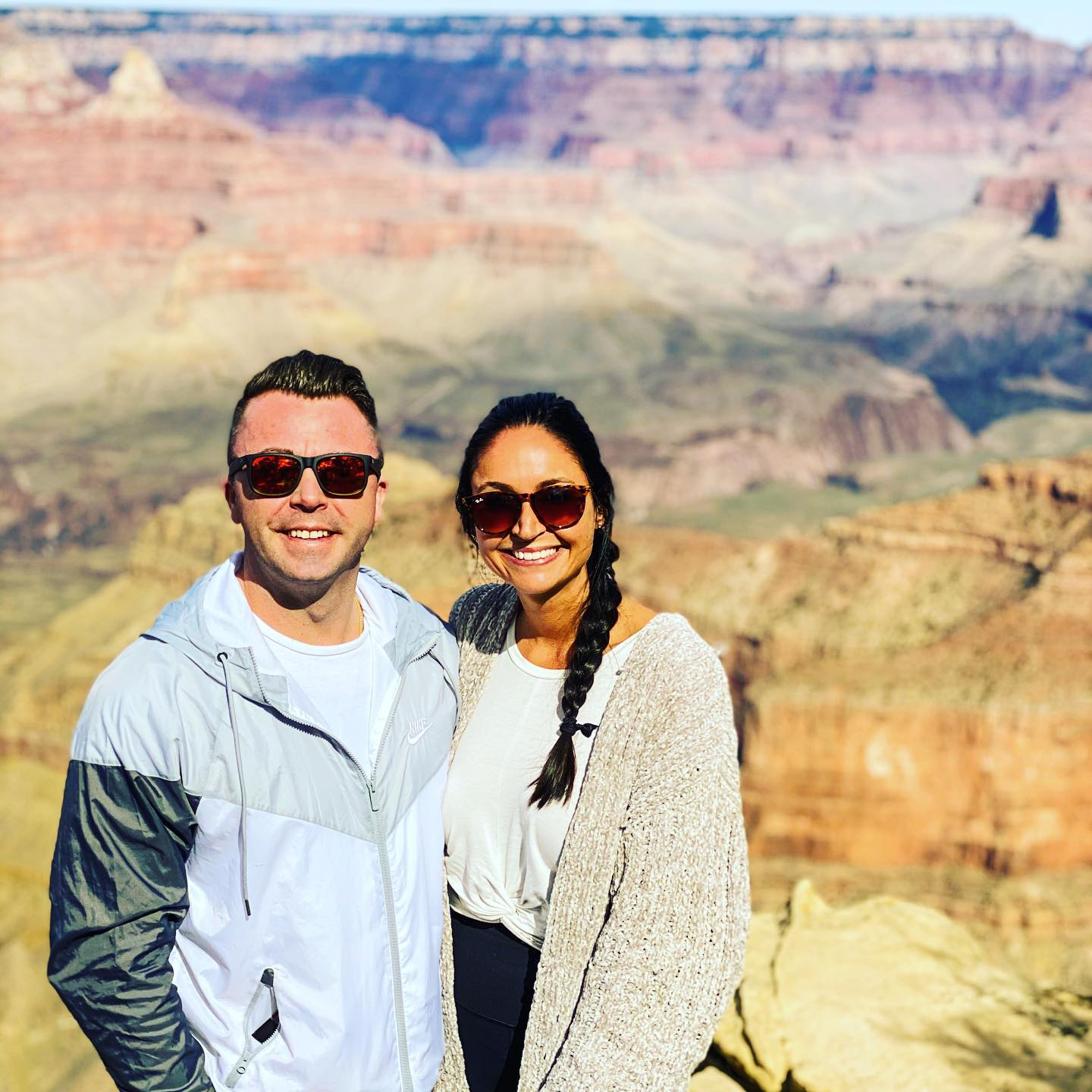 A man and a woman are posing for a picture in front of a canyon.