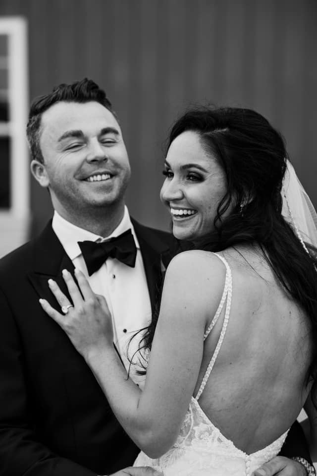 A black and white photo of a bride and groom smiling at each other.