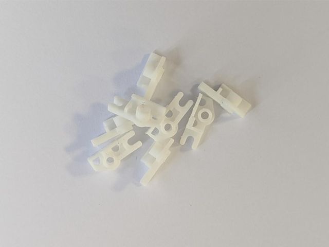 Small white 3D printed replacement clips for a Walkman